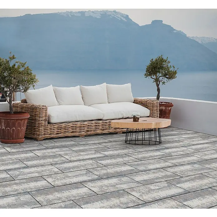 Terrassenplatte Latina - 48 x 24 x 3 cm, Mediterran, Beton - Wicker Sofa mit Couchtisch auf einer Terrasse mit Meerblick im Hintergrund.