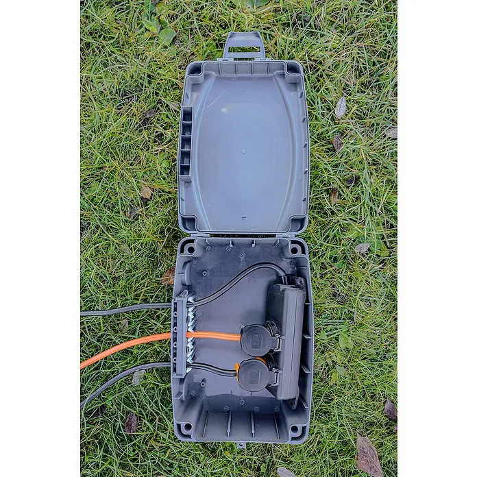 Brennenstuhl Kabelbox - L x B x H: 34 x 23 x 12,5 cm, IP54 - Eine geöffnete, graue Elektrobox auf einer Rasenfläche. Im Inneren befinden sich Kabel, ein Verteilerblock und Anschlüsse.