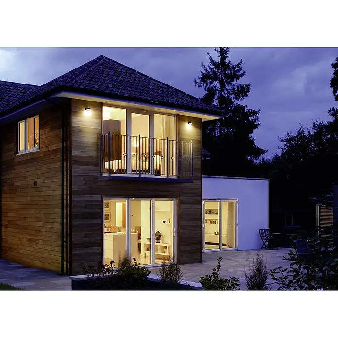 Ledvance LED-Außenwandleuchte Endura Style Mini Spot - 8 W, 100 x 230 x 54 mm, Grau, IP44 - Eine moderne Hausfassade mit Holzelementen und Außenbeleuchtung, die eine einladende Atmosphäre schafft. Die Beleuchtung setzt architektonische Details in Szene.