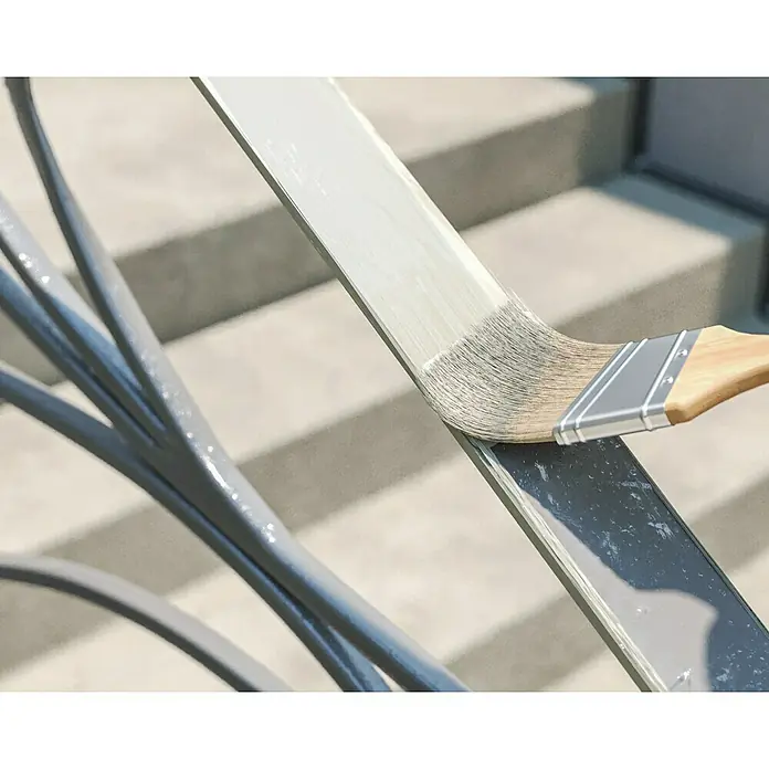 swingcolor Buntlack Kunstharz für Außen - Cremeweiß, Hochglänzend, 125 ml, Lösemittelbasiert - Das Foto zeigt einen Pinsel, der einen Metallhandlauf mit grauer Farbe streicht. Der Pinsel hat einen Holzgriff und silberne Borsten.