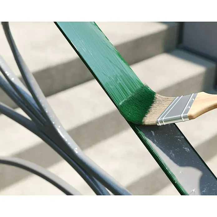 swingcolor Buntlack Kunstharz für Außen - Moosgrün, Hochglänzend, 750 ml, Lösemittelbasiert - Pinsel mit grüner Farbe streicht ein Metallgeländer, wobei die frische Farbe deutlich sichtbar ist. Die Farbauftragstechnik ist gut erkennbar.