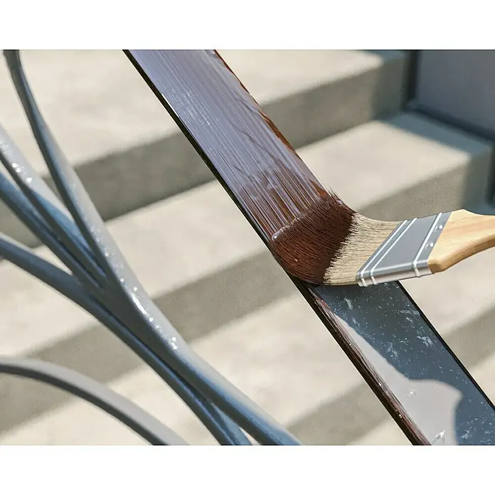 swingcolor Buntlack Kunstharz für Außen - Nussbraun, Hochglänzend, 125 ml, Lösemittelbasiert - Ein Pinsel trägt braune Farbe auf ein Metallgeländer auf, um es vor Witterungseinflüssen zu schützen und ihm ein neues Aussehen zu verleihen.