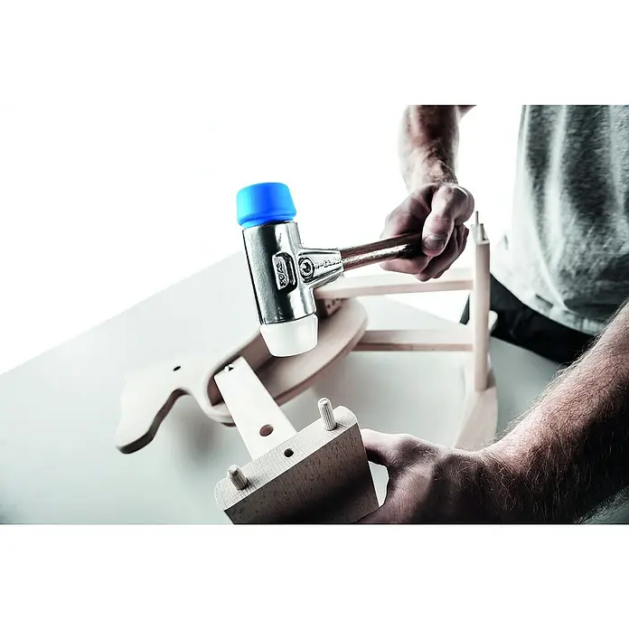 Halder Simplex Schonhammer TPE-Soft/MIDDurchmesser Kopf: 40 mm, Aluminium - Nahaufnahme eines Mannes, der mit einem Schonhammer ein Holzbauteil eines Kinderstuhls montiert. Der blaue Hammerkopf schützt das Holz vor Beschädigungen.