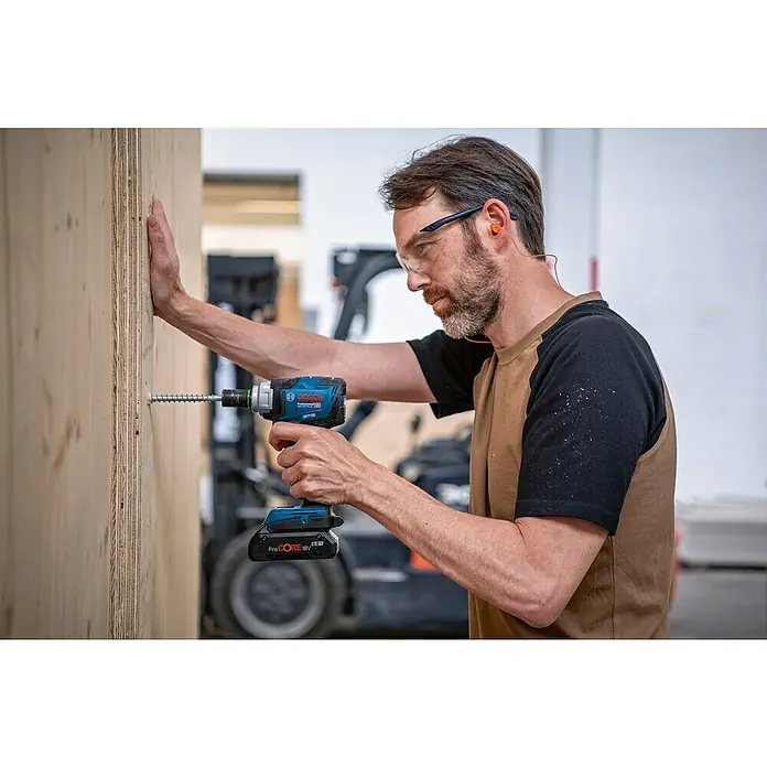 Bosch Professional AMPShare 18V Akku-Drehschlagschrauber GDS 18V-330 HC - 18 V, Ohne Akku, Max. Drehmoment: 330 Nm - Ein Mann befestigt mit einer Bosch Akku-Bohrmaschine eine Schraube in einem Holzbrett. Der Akkuschrauber ist blau und hat einen schwarzen Griff.