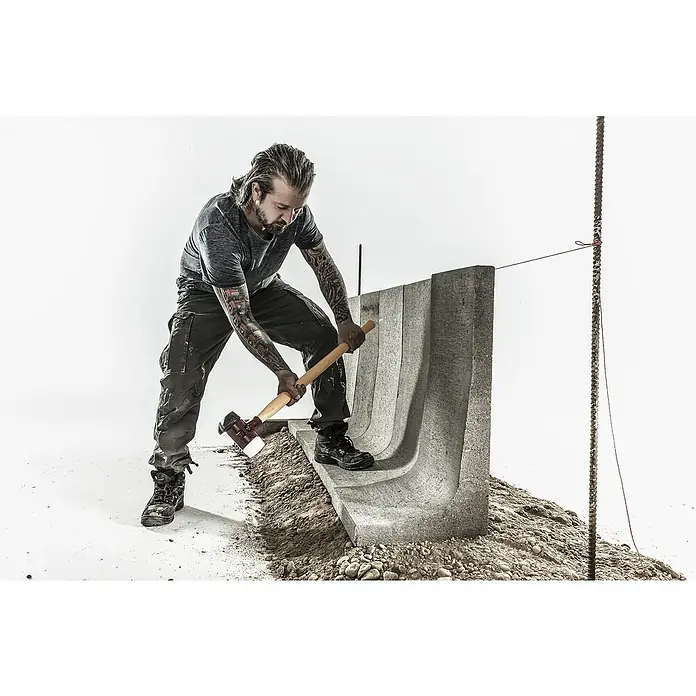 Halder Simplex Schonhammer Superplastik mit Standfuß - Durchmesser Kopf: 80 mm, Langstiel - Ein Mann mit Tätowierungen schlägt mit einem Hammer auf einen grauen Bordstein aus Beton. Er trägt Arbeitskleidung.