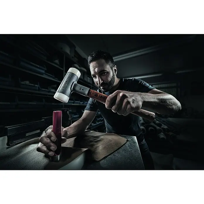 Halder Supercraft Schonhammer - Durchmesser Kopf: 40 mm, Holz - Ein Handwerker benutzt einen Supercraft-Hammer, um Leder zu bearbeiten. Der Hammer liegt im Fokus, während der Mann im Hintergrund arbeitet.