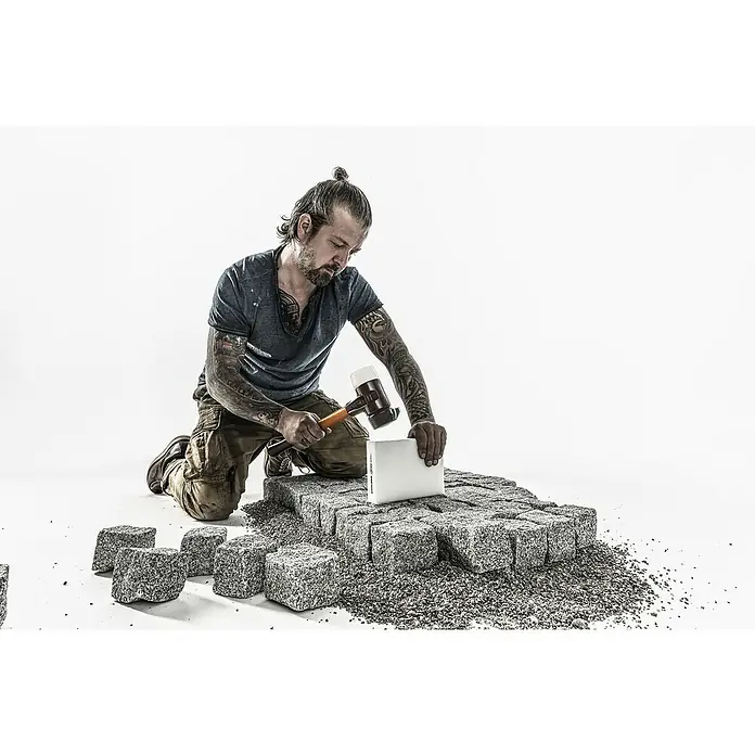 Halder Simplex Schonhammer Superplastik mit Standfuß - Durchmesser Kopf: 80 mm, Kurzstiel - Pflasterer mit einem Gummihammer bei der Arbeit, der einen Stein auf einem Pflasterweg fixiert. Handwerk und Straßenbau im Fokus.
