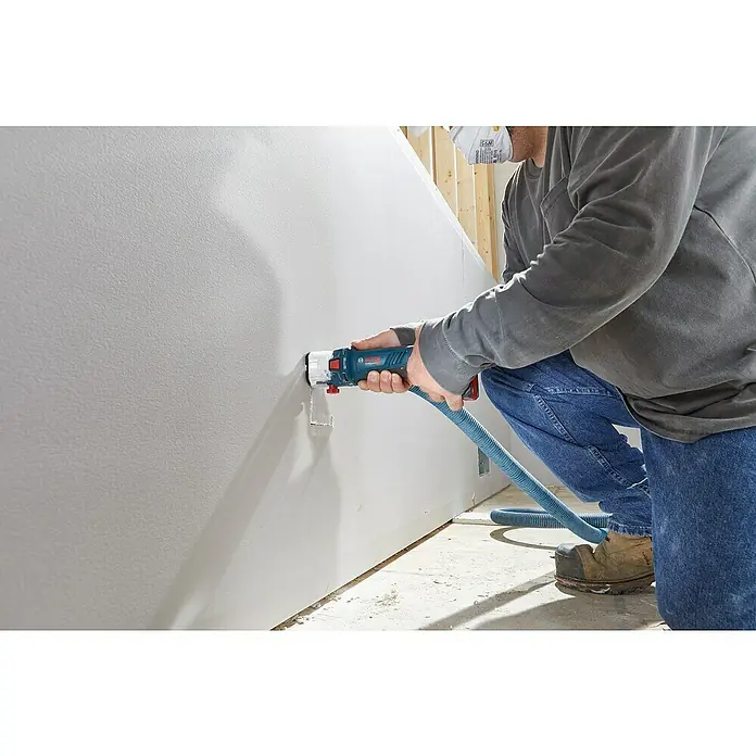 Bosch Professional AMPShare 18V Akku-Rotationswerkzeug GCU 18V-30 L - Ohne Akku, 18 V - Ein Handwerker benutzt ein Bosch-Elektrowerkzeug mit Staubsaugeranschluss, um ein Loch in eine Gipskartonwand zu schneiden.
