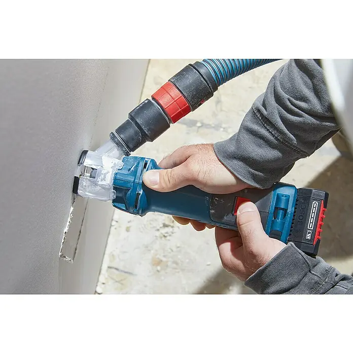 Bosch Professional AMPShare 18V Akku-Rotationswerkzeug GCU 18V-30 L - Ohne Akku, 18 V - Nahaufnahme einer Person, die ein Bosch-Elektrowerkzeug zum Schneiden von Trockenbauwänden mit Staubabsaugung verwendet.