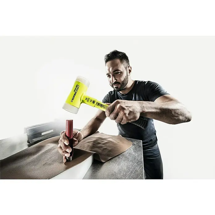 Halder Supercraft Schonhammer - Durchmesser Kopf: 50 mm, Kunststoff - Nahaufnahme eines Mannes, der mit einem Schalder Supercraft Schonhammer Leder bearbeitet, wobei der Fokus auf Werkzeug und Material liegt.