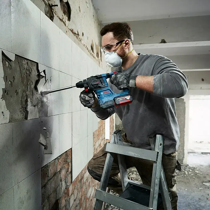 Bosch Professional AMPShare 18V Akku-Bohrhammer GBH 18V-22 - 18 V, Ohne Akku, 1,9 J - Ein Handwerker benutzt einen Bosch Bohrhammer, um Fliesen von einer Wand zu entfernen. Das Werkzeug ist kabellos und hat einen 18V Akku.