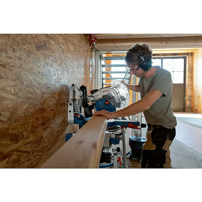 Bosch Professional AMPShare 18V Akku-Kapp- & Gehrungssäge GCM 18V-305 GDC Biturbo - 18 V, Ohne Akku, 2.550 U/min - 4.000 U/min - Ein Handwerker bedient eine Bosch Kapp- und Gehrungssäge, ausgestattet mit Gehörschutz und Schutzbrille, um Holz präzise zu bearbeiten.