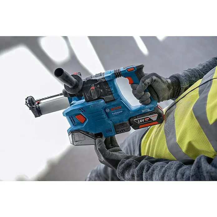 Bosch Professional Staubabsaugung GDE 18V-12 - Passend für: Bosch Professional Bohrhammer GBH 18V-22 - Nahaufnahme eines Bosch Professional Bohrhammers mit Staubabsaugung, gehalten von einer Person mit Arbeitshandschuhen.
