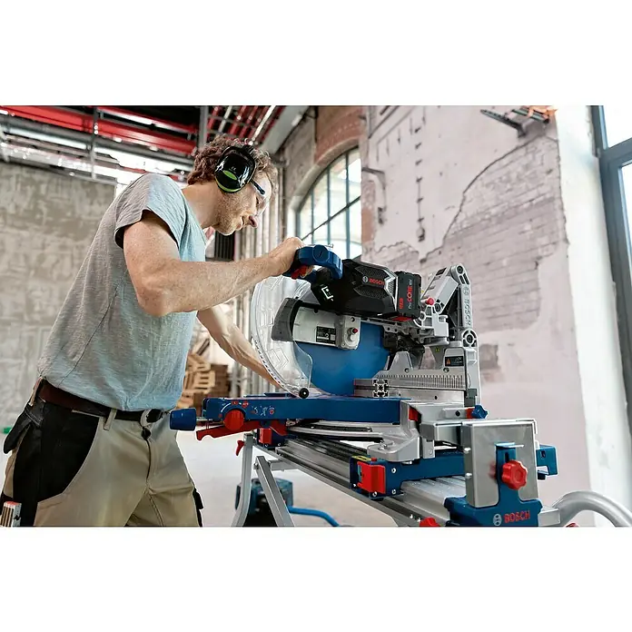 Bosch Professional AMPShare 18V Akku-Kapp- & Gehrungssäge GCM 18V-305 GDC Biturbo - 18 V, Ohne Akku, 2.550 U/min - 4.000 U/min - Ein Mann bedient eine Bosch Kapp- und Gehrungssäge mit Akku, ausgestattet mit blauem Sägeblatt und roter Batterie.