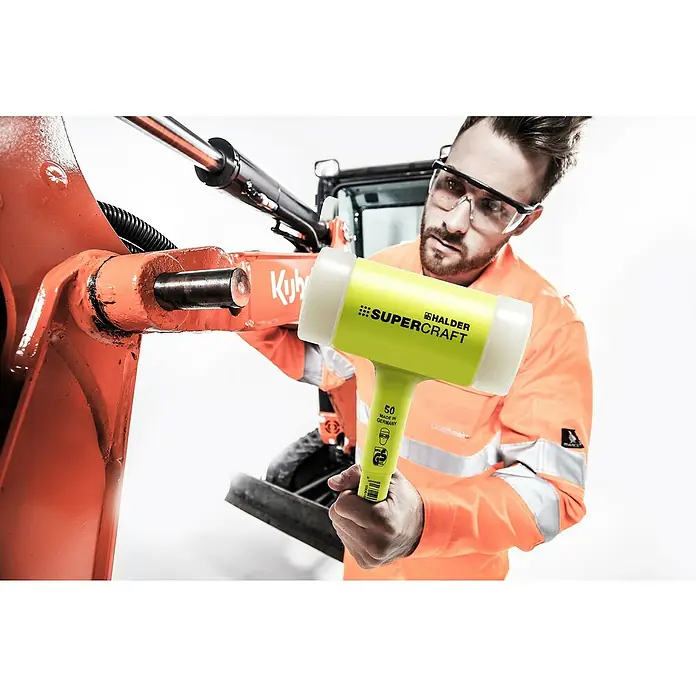 Halder Supercraft Schonhammer - Durchmesser Kopf: 50 mm, Kunststoff - Ein Mann benutzt einen gelben Halder SUPER CRAFT Hammer an einem orangefarbenen Bagger. Der Hammer ist gut sichtbar im Vordergrund.