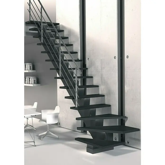 Sogem Escalera principal Gomera con barandilla - Valchromat® acabado óleo, Ancho: 85 cm, 1/4 espiral izquierda, Gris, Altura de planta: 285,2 cm - Primer plano de una escalera moderna con barandillas plateadas, sujeta a una pared de hormigón, que complementa un interiorismo minimalista.