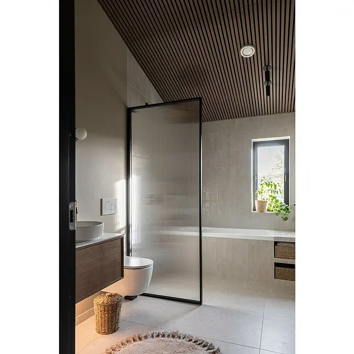 FibroTech Akustikpaneel Unika 25 - Walnut, 2.440 x 600 x 22 mm - Dieses Badezimmer verfügt über eine moderne Duschkabine mit geriffeltem Glas, einen Waschtisch aus Holz und eine stilvolle Holzdecke.