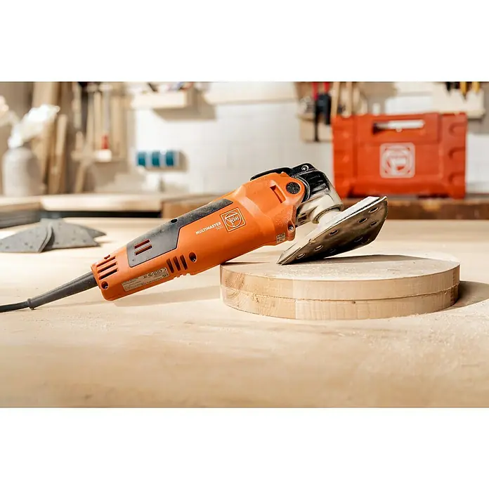 Fein Elektro-Multifunktionswerkzeug MultiMaster MM 500 Plus - 350 W, STARLOCK-System - Fein Multimaster 500, ein oszillierendes Elektrowerkzeug, das auf einem Holzkreis steht, ideal zum Schleifen und Sägen mit hoher Präzision.