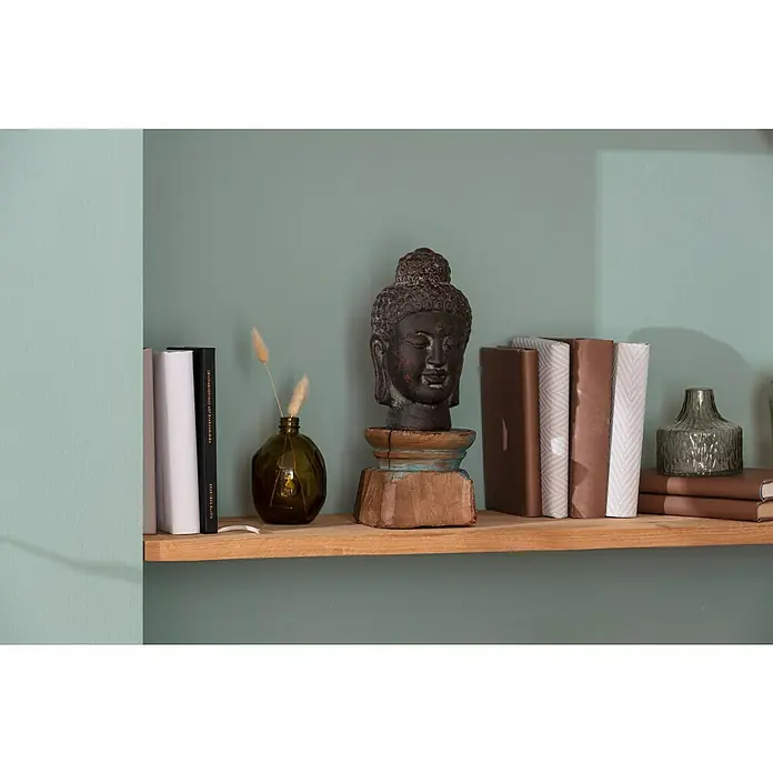 Buddhakopf - 17 x 31 cm, Dunkelgrau - Ein Regal mit Büchern, einer Buddha-Statue und einer Vase mit Pflanzen. Der Hintergrund ist eine mintfarbene Wand, die für eine ruhige Atmosphäre sorgt.