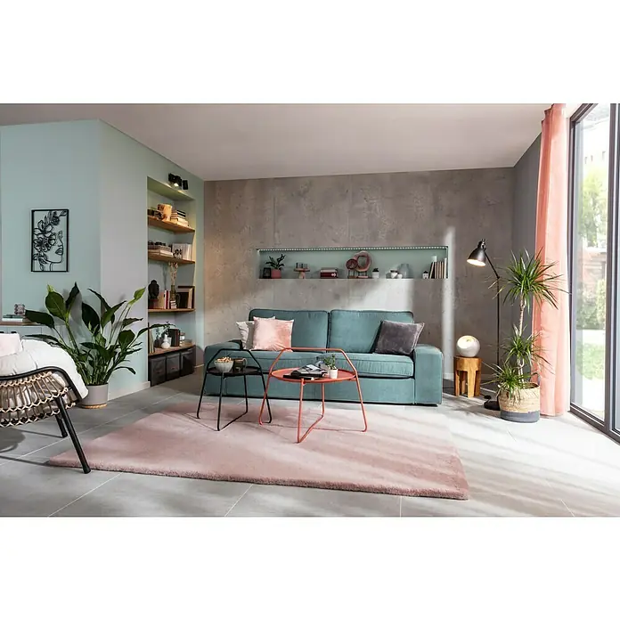 SCHÖNER WOHNEN-Farbe Naturell Wandfarbe KreidefarbeEukalyptuswald - kräftiges Blaugrün, Matt, 1 l, Konservierungsmittelfrei - Wohnzimmer mit mintgrünen Wänden, grauer Akzentwand, Bücherregal, Sofa mit Kissen, Tischchen und rosa Teppich für eine gemütliche Atmosphäre.