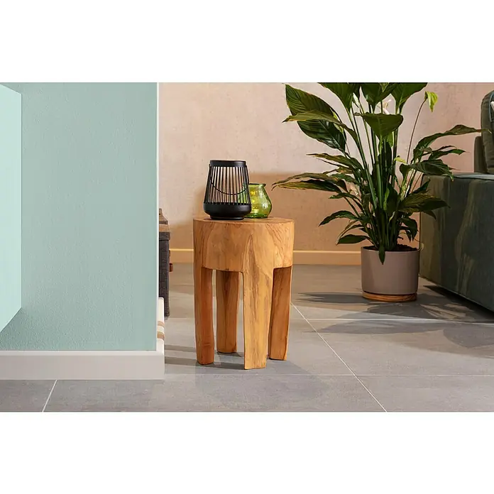 Hocker - Teak, Unbehandelt, Ø x H: 28 x 40 cm - Ein Holzhocker mit einer schwarzen Laterne und einer grünen Vase darauf, neben einer Zimmerpflanze.