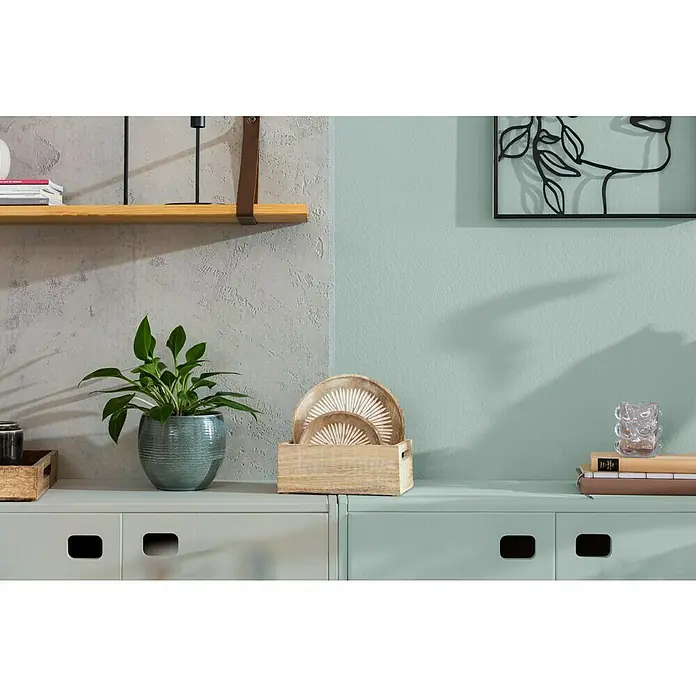 SCHÖNER WOHNEN-Farbe Naturell Wandfarbe KreidefarbeEukalyptuswald - kräftiges Blaugrün, Matt, 1 l, Konservierungsmittelfrei - Dekoratives Interieur mit Pflanzen, Holzschale und Bücherstapel auf einer modernen Anrichte, die eine stilvolle Atmosphäre schafft.