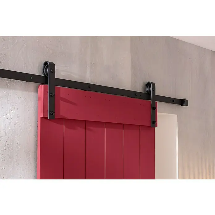 SCHÖNER WOHNEN-Farbe Wandfarbe Designfarbe - Gefühlvolles Herzensrot, Matt, 2,5 l, Konservierungsmittelfrei - Eine rote Schiebetür mit schwarzer Schiene und Beschlägen vor einer hellgrauen Wand. Das robuste Design verleiht dem Raum einen rustikalen Charme.