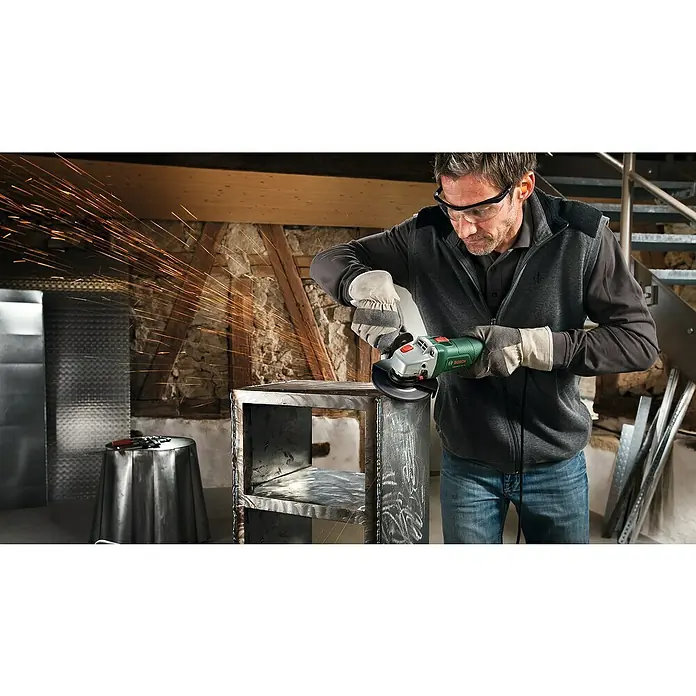 Bosch Universal Amoladora angular eléctrica Grind 750-115 - 750 W, Diámetro disco: 115 mm, 12.000 r.p.m. - Un hombre amuela una estructura de metal con una amoladora angular Bosch, saltan chispas. El hombre lleva ropa protectora.