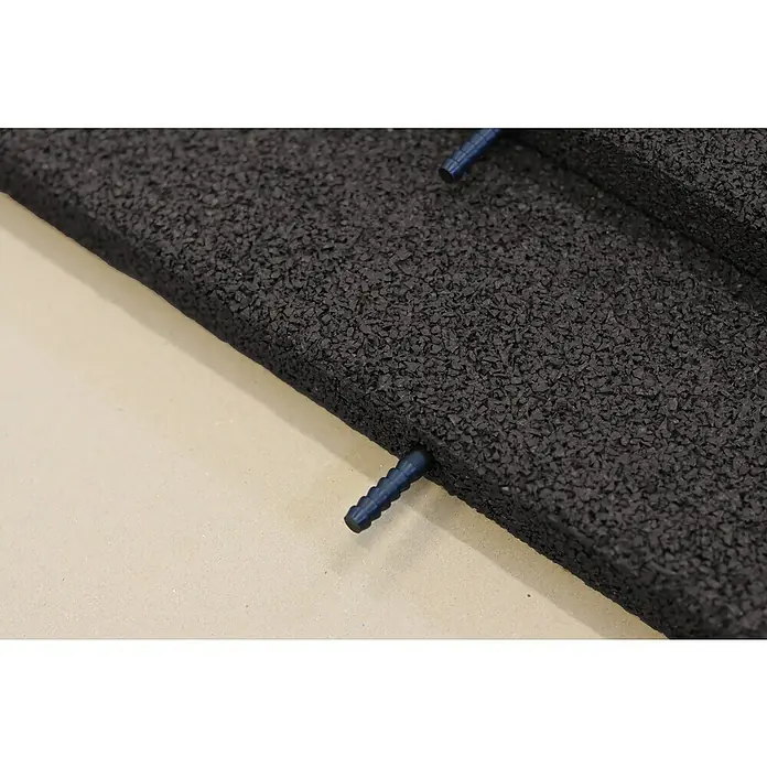 Fallschutzmatte inkl. Steckverbindung - Anthrazit, 50 x 50 x 3 cm - Nahaufnahme einer schwarzen Gummimatte mit blauen Stiften, die Oberfläche ist rau und körnig, ideal für Fitnessstudios oder Spielplätze.