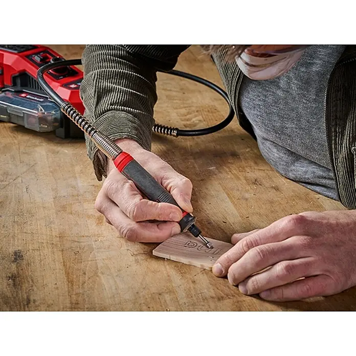 Einhell Power X-Change 18V Schleif- & Gravurwerkzeug TE-MT 18/34 Li-Solo - Ohne Akku, 5.000 U/min - 34.000 U/min - Nahaufnahme einer Person, die mit einem Einhell-Rotationswerkzeug ein Stück Holz bearbeitet, das Vielseitigkeit für detaillierte Projekte bietet.