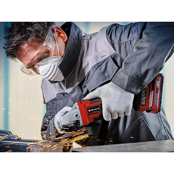 Einhell Professional PXC 18V Amoladora angular de batería TP-AG 18/125 CE Q Li - Solo - Sin batería, Diámetro disco: 125 cm, 3.000 r.p.m. - 10.500 r.p.m. - Un artesano utiliza una amoladora angular inalámbrica Einhell para esmerilar metal, con chispas. Se usa equipo de protección.