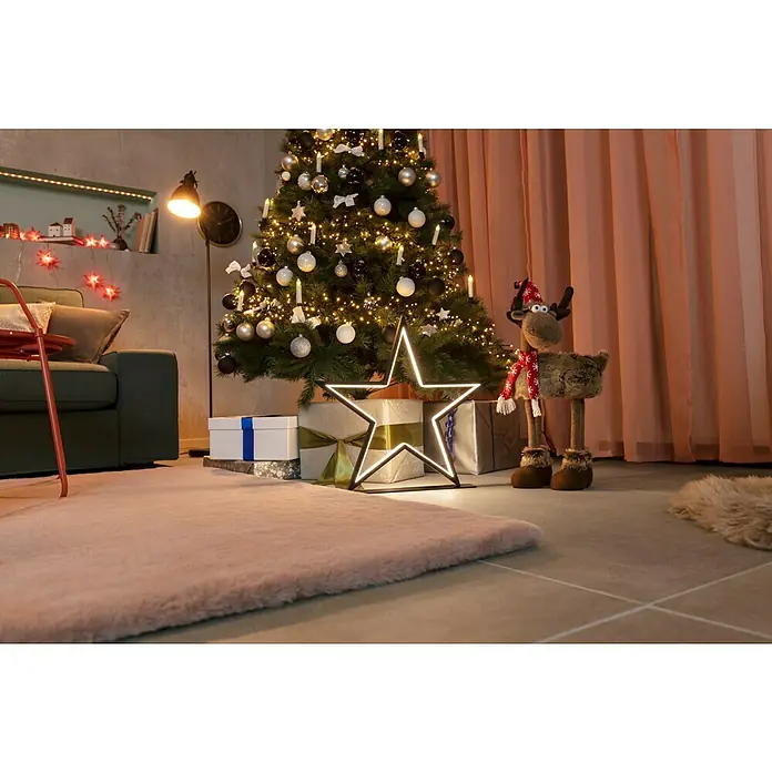 Dekofigur Elch mit Mütze - L x B x H: 35 x 15 x 53 cm, Kunststoff, Rentier - Festliche Szene mit geschmücktem Weihnachtsbaum, Geschenken und einer leuchtenden Sternendekoration, die eine gemütliche Weihnachtsatmosphäre schafft.
