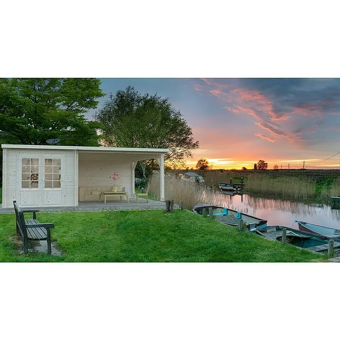 Palmako Gartenhaus Ella - Außenmaß inkl. Dachüberstand (B x T): 614 x 340 cm, 16,9 m², Holz, Natur - Ein Holzhaus mit überdachter Terrasse und Sitzmöbeln, eingebettet in eine malerische Landschaft mit Wasserblick.