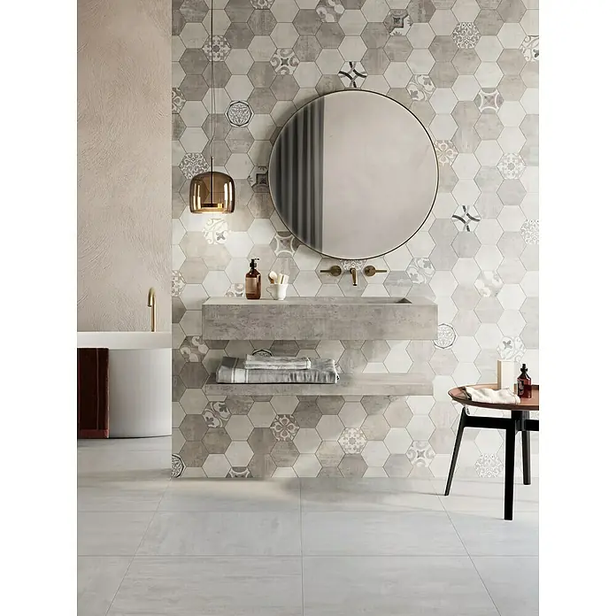 Atlas Concorde Solution Yorkshire Mosaikfliese Hexagon Warm - 25,3 x 33 cm, Beige/Braun, Matt - Elegantes Badezimmer mit sechseckigen Wandfliesen in Grau- und Weißtönen, einem runden Spiegel und einer modernen Waschtischkonstruktion.