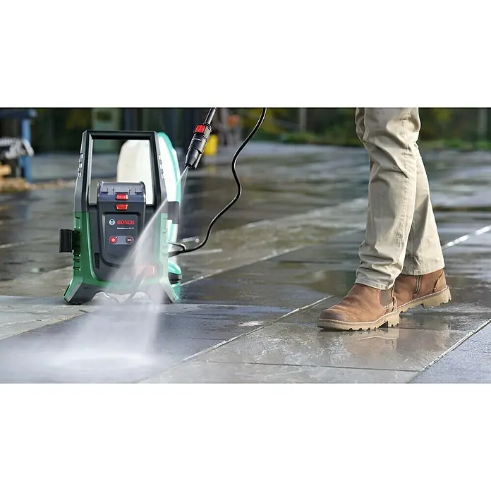 Bosch Universal Akku-Hochdruckreiniger UniversalAquatak 36V-100 - 8 -tlg., 36 V, 1 Akku - Der Bosch Hochdruckreiniger entfernt Schmutz von einer Steinterrasse, während eine Person daneben steht.