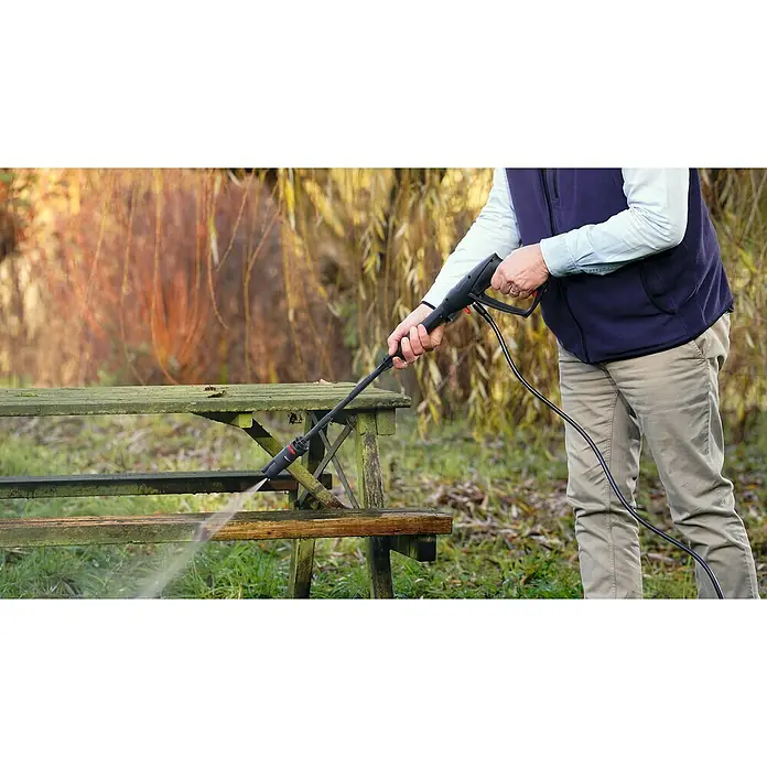 Bosch Power for All 36V Akku-Hochdruckreiniger UniversalAquatak 36V-100 - 5 -tlg., 36 V, Ohne Akku - Eine Person reinigt mit einem Hochdruckreiniger einen Holztisch im Freien, der Moos und Ablagerungen entfernt, um die Holzoberfläche wiederherzustellen.