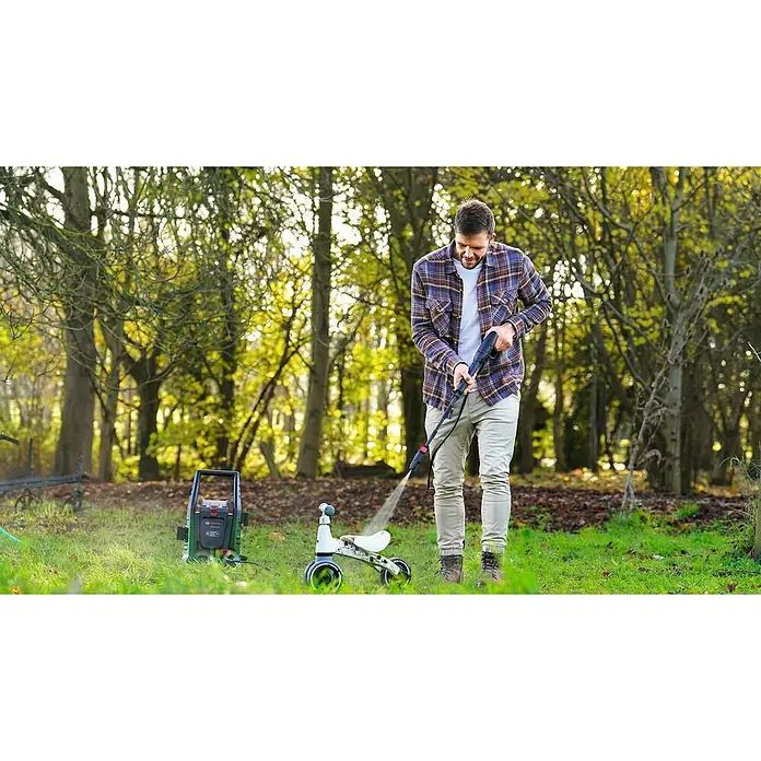 Bosch Power for All 36V Akku-Hochdruckreiniger UniversalAquatak 36V-100 - 5 -tlg., 36 V, Ohne Akku - Mann reinigt ein Dreirad mit einem Bosch Hochdruckreiniger im Freien. Der Reiniger steht auf dem Rasen, während der Mann das Spielzeug abspritzt.
