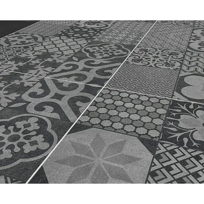 Ambiente by Palazzo Feinsteinzeugfliese Vintage60 x 60 cm, Schwarz, Matt - Das Bild zeigt ein Muster aus dekorativen Bodenfliesen in verschiedenen Designs und Grautönen, die ein stilvolles und elegantes Ambiente erzeugen.