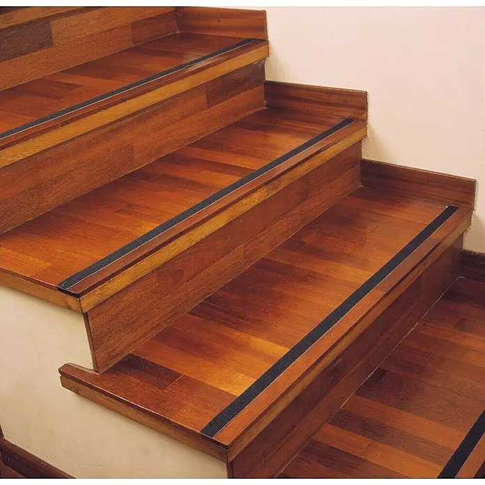 Inofix Cinta antideslizante 1990 - L x An: 5 m x 50 mm, Negro - Foto de escaleras de madera con peldaños antideslizantes negros para mayor seguridad y un mejor agarre al subir y bajar.