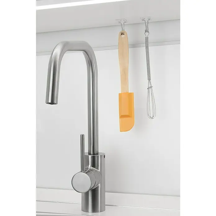 Inofix Gancho para colgar 2106 - Transparente, 2 ud. - Primer plano de un moderno grifo de cocina de acero inoxidable con una espátula y un batidor colgando de ganchos transparentes.