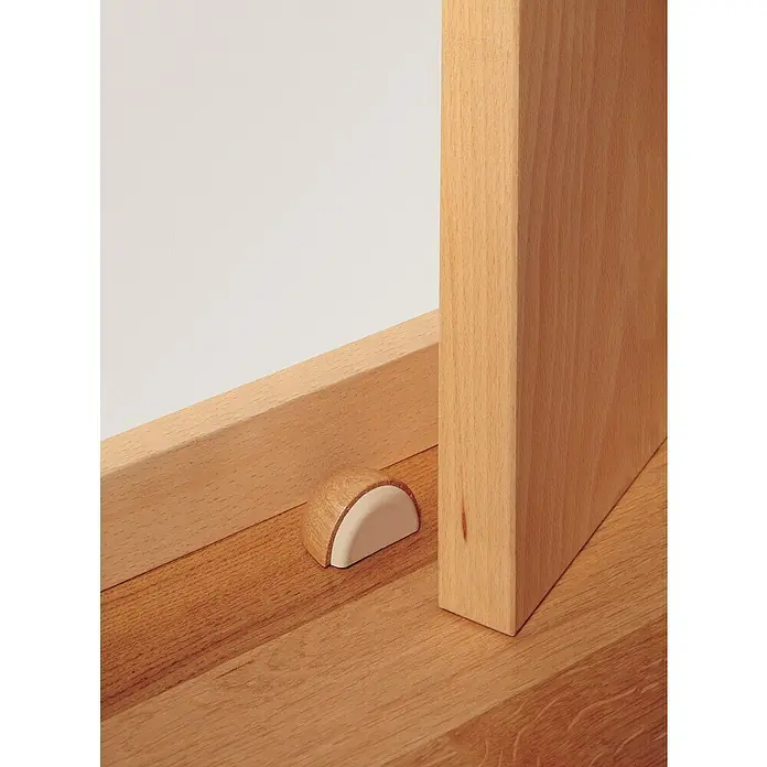 Inofix Tope de puerta 2039 - Madera, Haya, 1 ud. - Primer plano de un tope de puerta de madera que mantiene una puerta abierta, sentado en un suelo de madera.