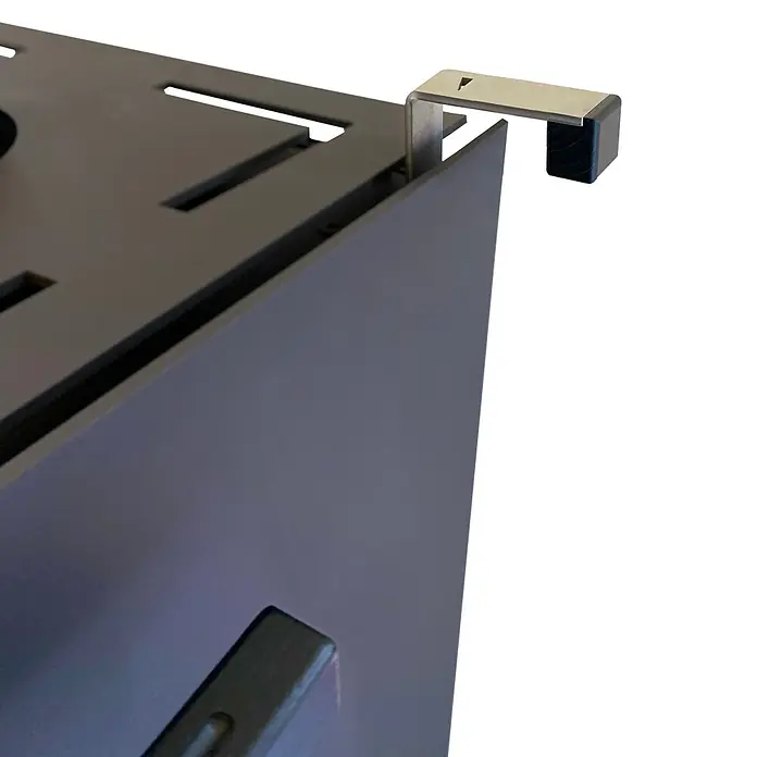 xeoos Kaminofen Patagonia X5 - 5 kW, Raumheizvermögen: 20 m³ - 70 m³, Farbe Verkleidung: Anthrazit - Nahaufnahme eines Gerätes, das eine metallische Halterung zur Befestigung an einer Tischkante besitzt. Die Halterung ist modern und funktional gestaltet.
