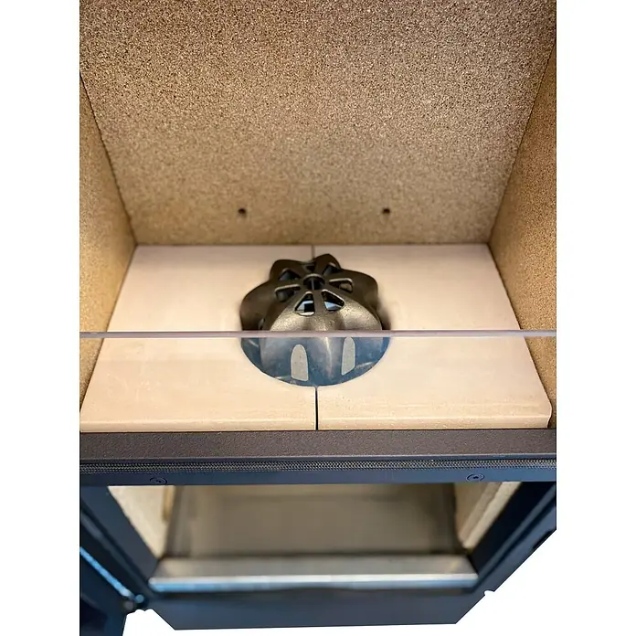 xeoos Kaminofen Patagonia X5 - 5 kW, Raumheizvermögen: 20 m³ - 70 m³, Farbe Verkleidung: Anthrazit - Ansicht in einen Holzofen mit keramischen Innenleben und einer gusseisernen Abdeckung.