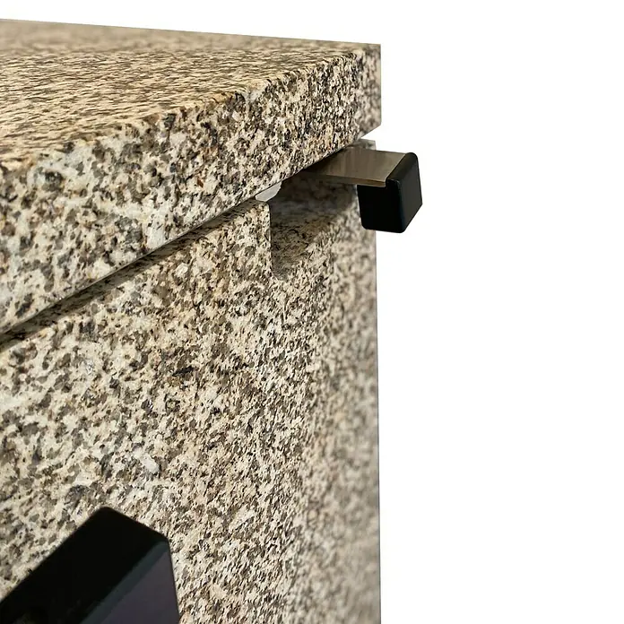xeoos Kaminofen Patagonia X5 - 5 kW, Raumheizvermögen: 20 m³ - 70 m³, Farbe Verkleidung: Ming Yellow - Detailaufnahme eines Granit-Tresens mit einer stabilen, metallenen Tresenstütze, die durch einen schwarzen Block verstärkt wird.