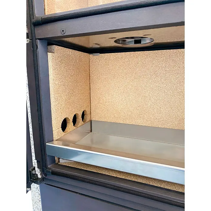 xeoos Kaminofen Patagonia X5 - 5 kW, Raumheizvermögen: 20 m³ - 70 m³, Farbe Verkleidung: Ming Yellow - Detailaufnahme eines modernen Kaminofens mit Innenraum aus hellem, isolierendem Material und einer glänzenden Metallablage.