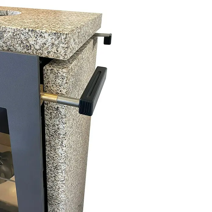 xeoos Kaminofen Patagonia X5 - 5 kW, Raumheizvermögen: 20 m³ - 70 m³, Farbe Verkleidung: Ming Yellow - Nahaufnahme eines Ofens mit einer Tür und einem Griff aus Stein und Metall, der Wärme und Eleganz vereint.