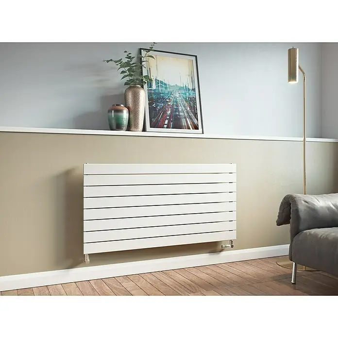 Ximax Raumheizkörper P1 Horizontal - B x H: 595 x 1.000 mm, Wärmeleistung bei Vorlauftemperatur von 75 °C (D: 50): 634 W, Weiß - Abbildung eines weißen Heizkörpers an einer Wand unter einem Regal mit Dekorationen. Eine stilvolle Heizlösung für moderne Wohnräume.