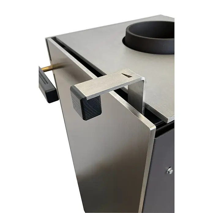 xeoos Kaminofen Patagonia X5 - 5 kW, Raumheizvermögen: 20 m³ - 70 m³, Farbe Verkleidung: Inox Edelstahl - Nahaufnahme einer Metallkaffeemaschine mit einem Griff aus dunklem Holz und Metallelementen. Die glatte Oberfläche und das schlichte Design fallen auf.