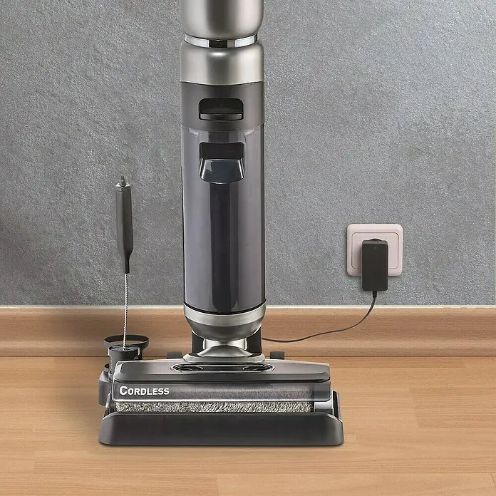 Thomas Akku-Hartbodenreiniger Aqua Floor Cleaner Cordless - 21,6 V - Das Bild zeigt einen kabellosen Staubsauger, der zum Aufladen an eine Steckdose angeschlossen ist.