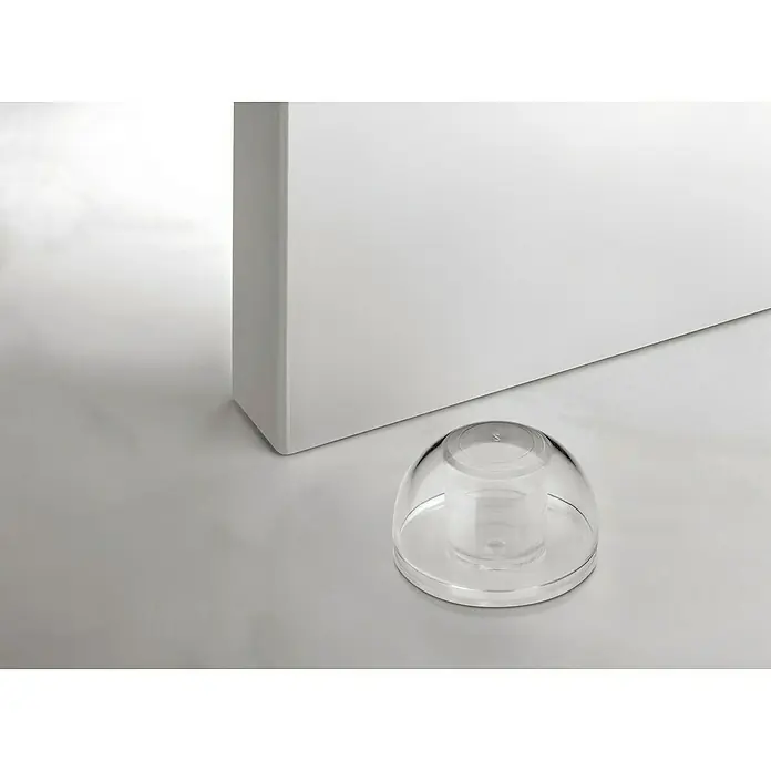Inofix Tope de puerta 2033 - Transparente, Plástico, 2 ud. - Primer plano de un tope de puerta transparente, situado junto a una puerta blanca sobre un suelo liso y de color claro.